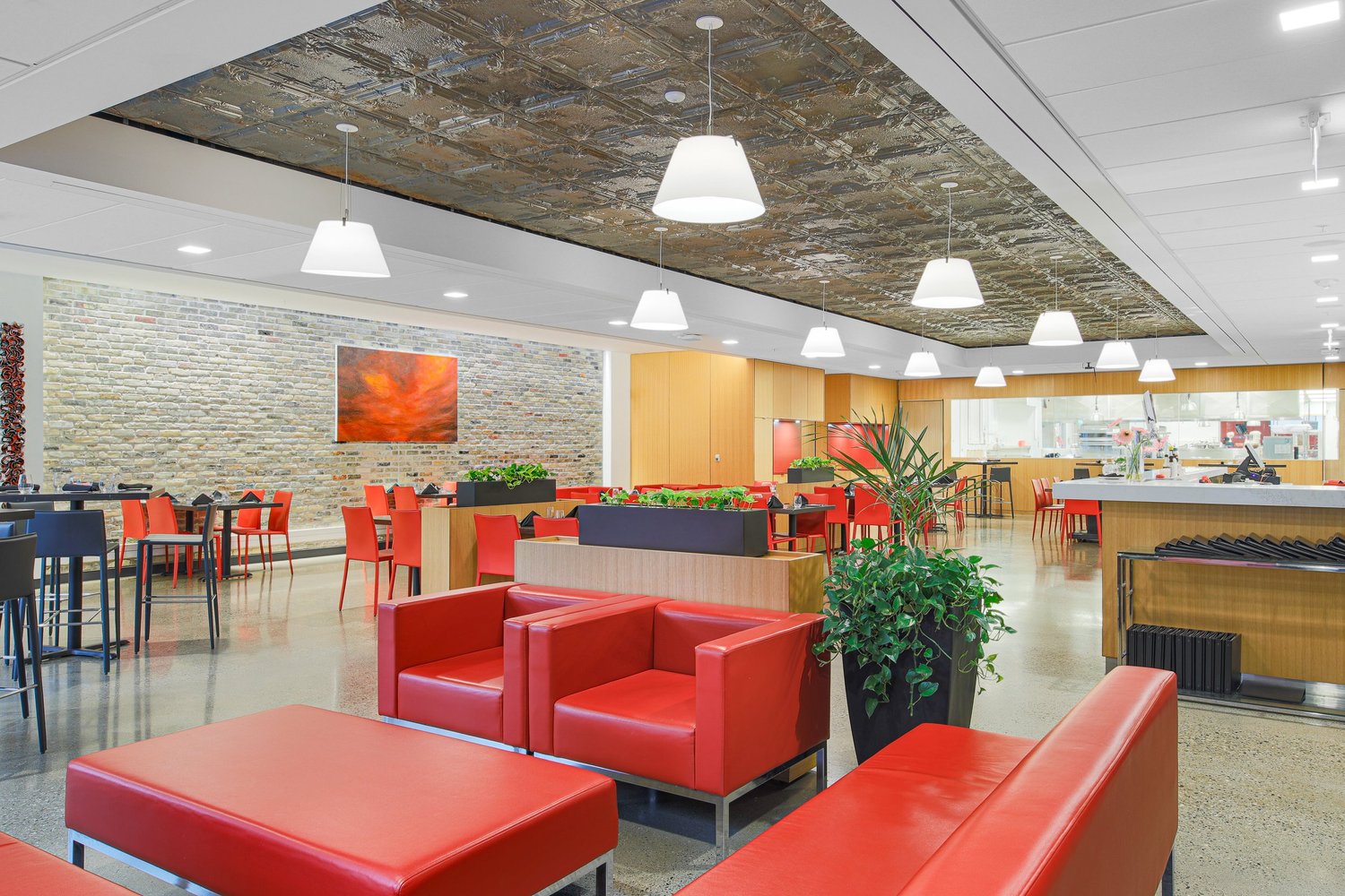 A wide view of a restaurant interior with red lounge seating and dining tables.