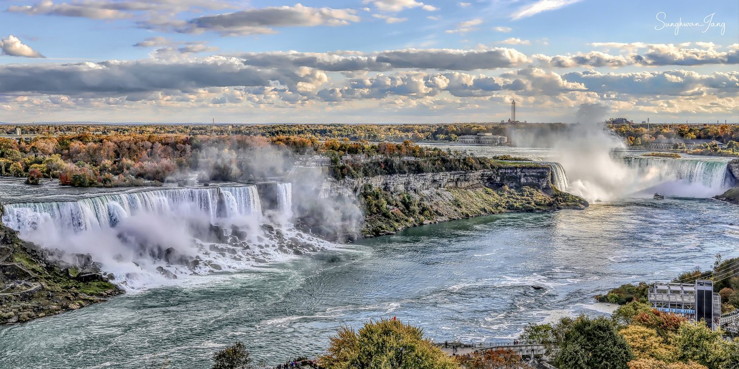 Niagara Falls and autumn foliage beneath a cloud-filled sky.